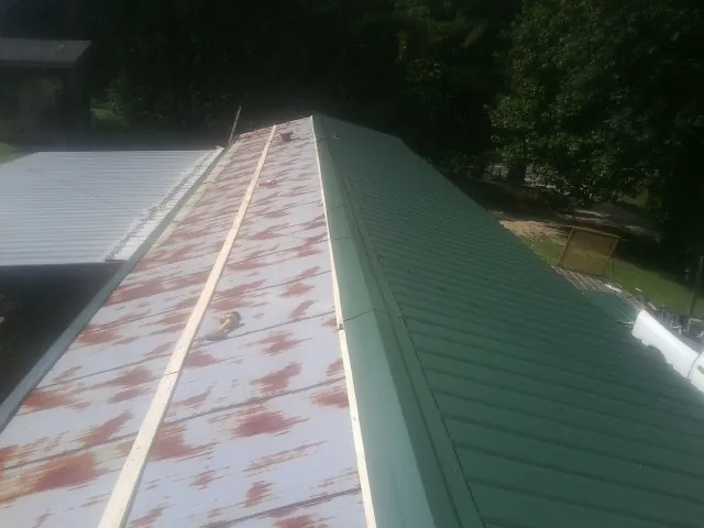 Old rusted panels beside newly installed green metal roofing — Wind Damage Roof Repair by Roofing Brothers in East Lansing
