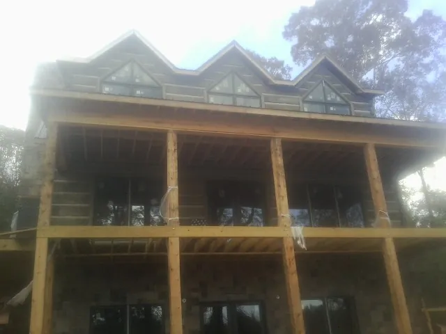 Dormers and porch framing on a large log home under construction — Roof Coating work by our crew in East Lansing