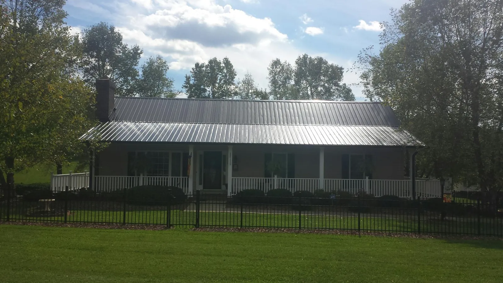 Gray metal roof on a brick ranch with a full width front porch — Gutter Guard Installation work by our crew in East Lansing