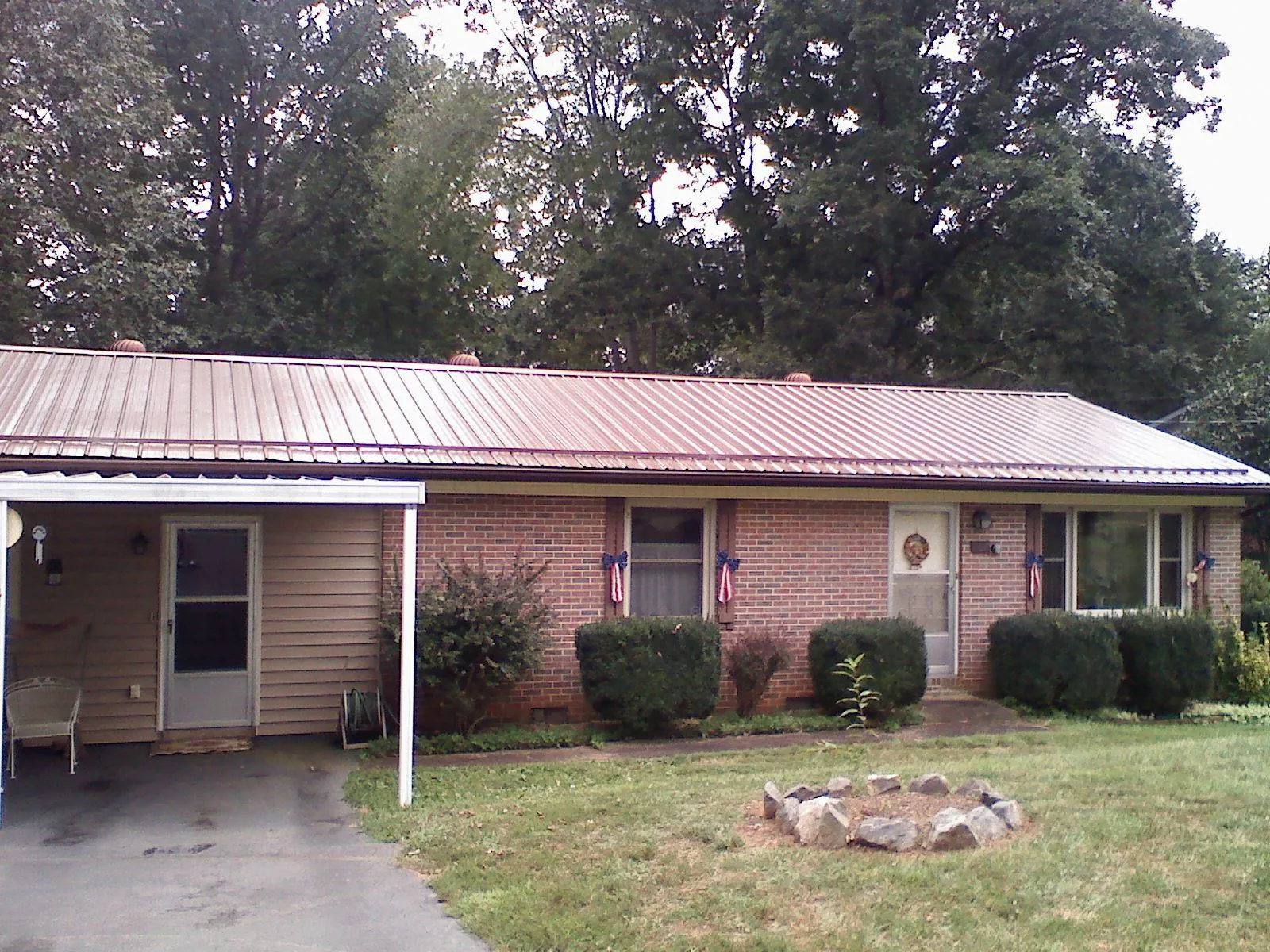 Bronze metal roof and carport on a brick ranch home — Roof Repair work by our crew in East Lansing