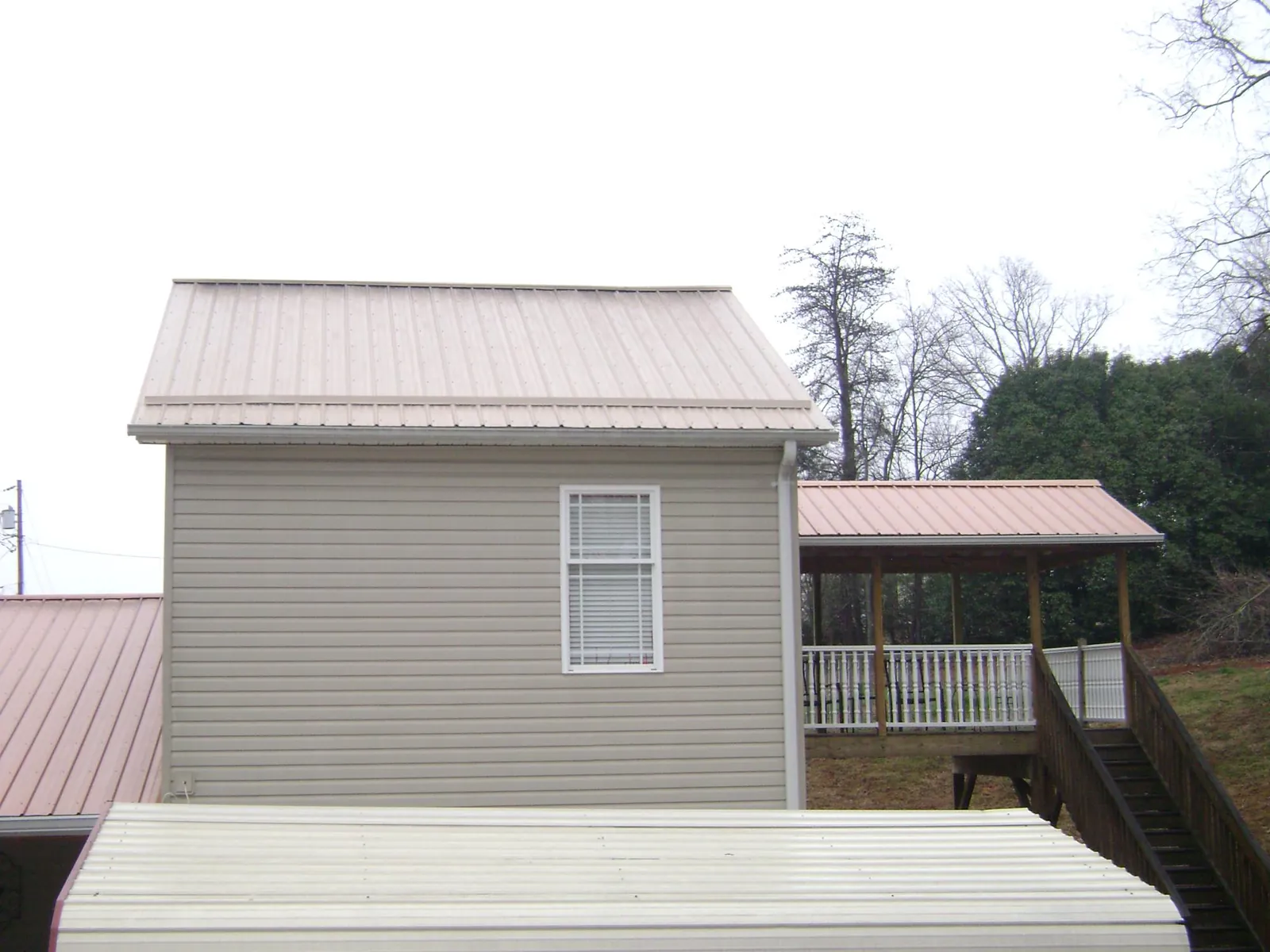 Tan metal roofs on a two story addition and attached porch, from a Roof Replacement job in East Lansing