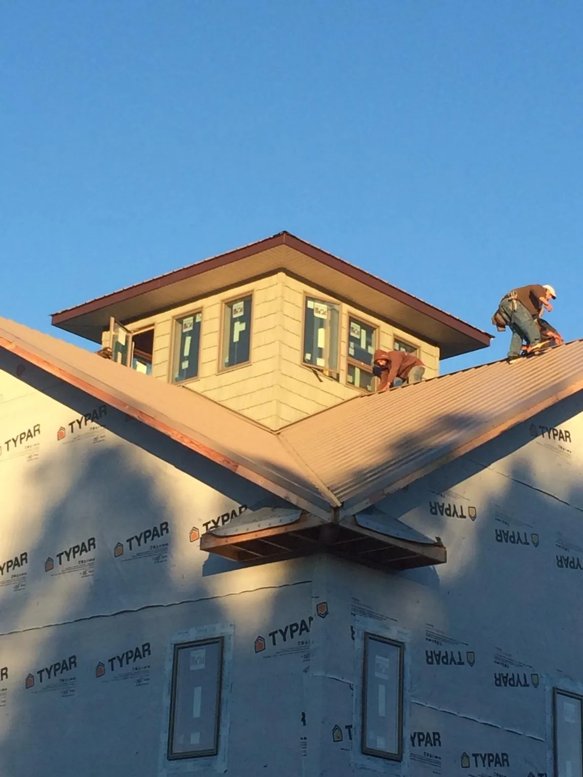 Roofers working around a rooftop cupola on a new metal roof at sunset — Roof Waterproofing in East Lansing by Roofing Brothers